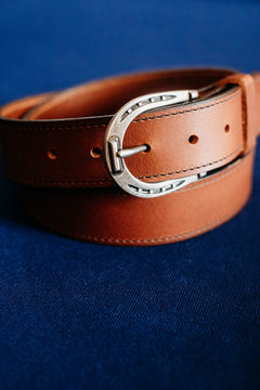 The Shoe full grain leather belt, horseshoe buckle close-up in golden brown
