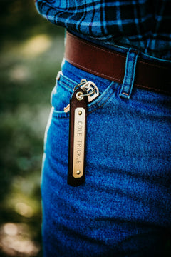 Leather nameplate keytag with engraved brass plate clipped to jeans belt loop