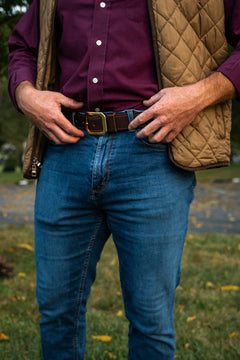Kayce chocolate water buffalo belt with brass western buckle, worn with jeans