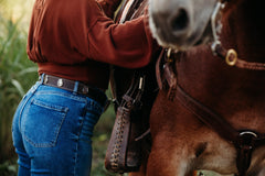 Claire water buffalo belt worn with jeans, horseshoe concho detail